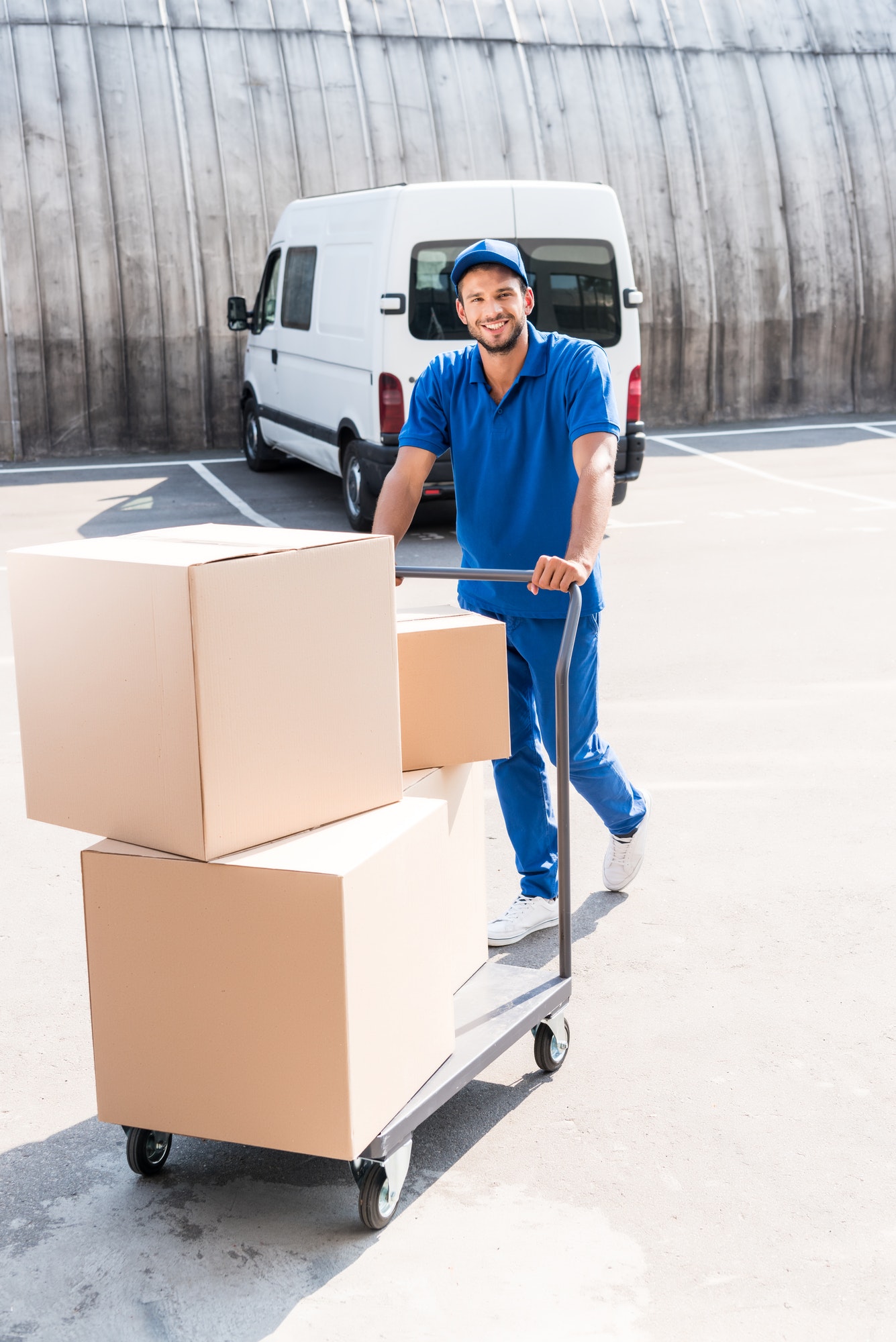 happy delivery man with cardboard boxes on cart.jpg